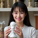 Professional headshot of Maya Lin, a merchandise designer proudly holding up a detailed collectible figure.
